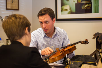 Man discussing a violin with a woman