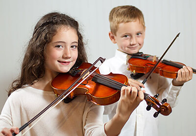 a girl and boy practice their violins